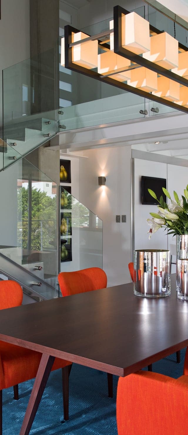 Sala de jantar moderna com cadeiras laranja e escada